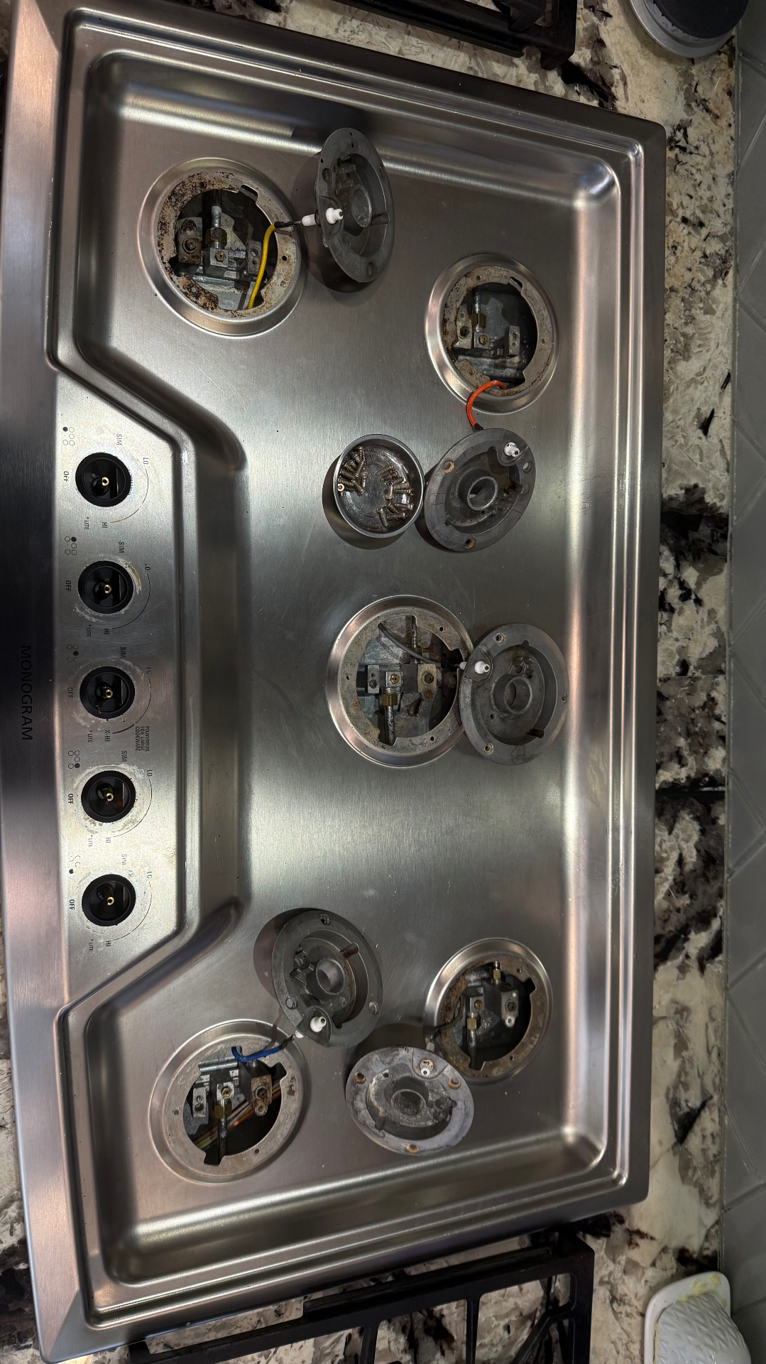 An opened gas cooktop with exposed parts